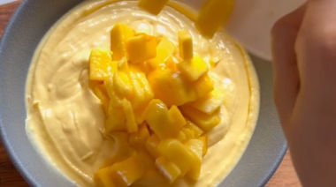 No-bake mango cheesecake jar topped with cream and fresh mango pieces